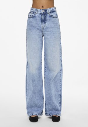 Lyseblå jeans med høj talje og vide ben båret med sorte sko med firkantet tå, vist fra talje til fødder på hvid baggrund.
