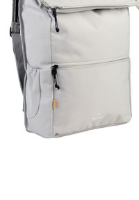 Lichtgrijze rugzak van duurzaam materiaal, met ritsen, zijvak van mesh en een kleine oranje accent. Merklogo gedrukt aan de voorkant.