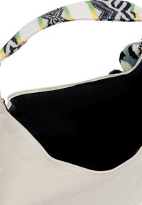 Borsa in canvas con un interno nero, dotata di chiusura zip e una tracolla con motivo nei colori bianco, giallo, verde e nero.