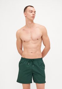 Grønne badetårn laget av lett materiale, med elastisk midjebånd og justerbar snor, med rett snitt og uten synlige mønstre.
