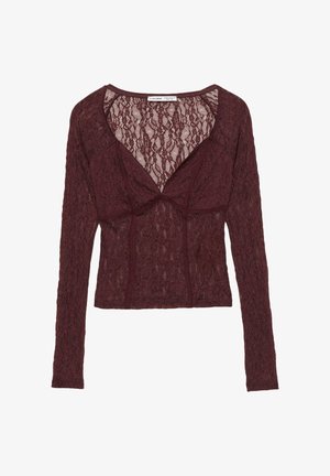 Burgunderfarbene Spitzenbluse mit langen Ärmeln und V-Ausschnitt, die über florale Muster und strukturierte Nähdetails verfügt. Leichter Stoff, taillierte Passform.