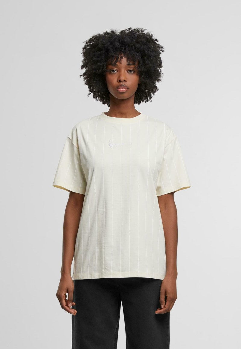 Camiseta de algodón amarilla clara con un ajuste relajado, mangas cortas y rayas blancas. Presenta un logo bordado en el pecho.