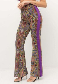 Pantaloni svasati colorati con motivi geometrici in tonalità di rosso, verde, blu e viola, con una striscia laterale viola solida.