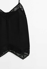 Camisole noire sans manches avec bordure en dentelle sur l'encolure et l'ourlet, dotée de fines bretelles et d'un ourlet subtilement en forme de V.