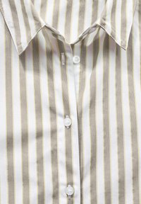 Camicia a maniche lunghe a righe con strisce bianche, beige e gialle. Presenta un colletto, bottoni frontali e una texture liscia.