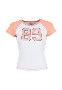 Tricou alb cu mâneci scurte, având mânecile raglan de culoare roz deschis. Prezintă un contur mare negru al cifrei "89" și un logo roșu asemănător unei semnături.