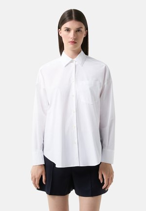 White long-sleeve shirt with a button-up collar, single chest pocket, and straight hem. Smooth texture and relaxed fit.