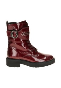 Red patent leather ankle boot with a rounded toe, lace-up design, decorative buckle, and studs on the strap. Thick black sole.