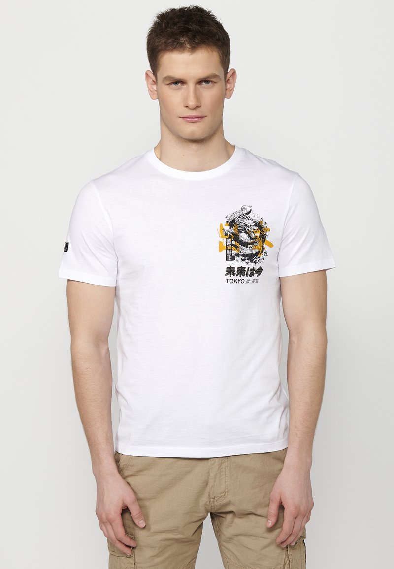 White cotton t-shirt with short sleeves, featuring a graphic print of a tiger and text in black and yellow on the front.