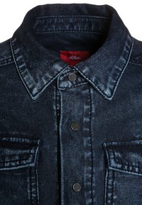 Dark blue denim jacket with collar, front snap buttons, two chest pockets, and a red brand label inside the collar.