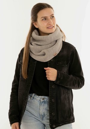 Lichtgrijze gebreide infinity-sjaal met een gemêleerd patroon, gedragen over een zwarte jas. Heeft een klein merketiketje op de sjaal.