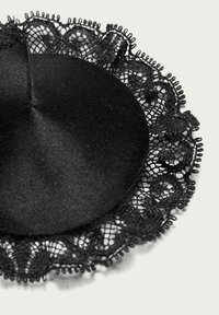 Accesorio de tejido negro que presenta una sección central suave con delicado encaje en el borde y bordes en forma de ondas. La textura es suave y cuenta con detalles intrincados.