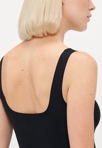 Black sleeveless top with a square back. Features a smooth texture and wide straps, highlighting the shoulder and upper back area.