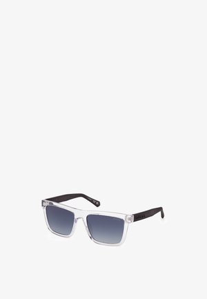 Gafas de sol de plástico transparente con lentes gris degradado y brazos negros. El diseño presenta una forma cuadrada y un sutil detalle del logo en la montura.