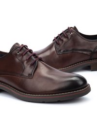 Chaussures habillées en cuir marron avec un bout rond, des lacets violet foncé et des coutures contrastées. Elles présentent une surface lisse et un talon modeste.