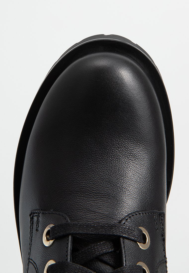 Chaussure en cuir noir avec bout rond, surface texturée, œillets en métal et lacets noirs, dotée d'une semelle en caoutchouc durable.