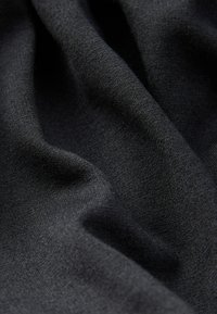 Tela negra con una textura suave, que presenta pliegues sutiles y una apariencia uniforme. No se observan patrones distintivos ni herrajes.