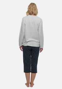 Lys grå langærmet top parret med navy blå og hvide stribede cropped bukser, med en afslappet pasform og bløde teksturer.