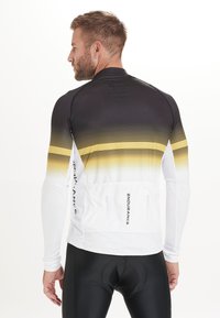 Langärmliges Radtrikot, schwarz-weißer Farbverlauf mit gelben Akzenten, aus dehnbarem Material gefertigt. Verfügt über ein aerodynamisches Design und Rückentaschen.