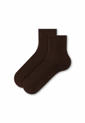Paar dunkelbraune gerippte Knöchelsocken flach auf weißem Hintergrund gelegt.