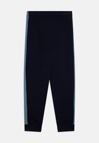 Mornarske trenirke s elastičnom trakom oko struka, s tirkiznim bočnim trakama. Mekani pamučni materijal, sužene nogavice i rebrasti manžeti na gležnjevima.