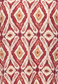 Red, orange, beige, and cream geometric diamond pattern with stepped edges on a textured fabric background.