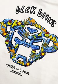 Witte t-shirt met kleurrijk grafisch ontwerp met blauwe, groene, gele en rode elementen, waaronder dieren, zonmotieven en geometrische vormen.