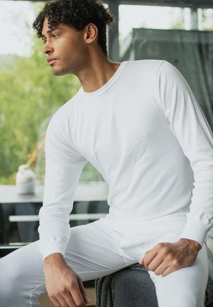 White long-sleeve shirt and matching pants made of soft fabric. Simple design with fitted sleeves and a crew neckline.