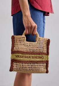 Geweven strohandtas met beige, groene en bruine strepen, voorzien van versterkte handvatten en de tekst "VANESSA BRUNO" op de voorkant.