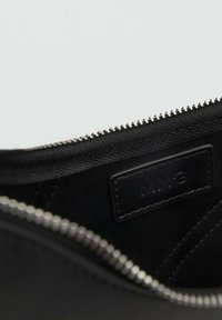 Black zippered pouch made of textured material, featuring a smooth lining and an embossed label, with a silver zipper along the top edge.