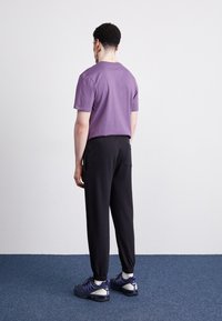 Violeta īsām piedurknēm T-kreklā, kas apvienots ar melniem pieguļošiem biksēm. Ikdienišķi sporta apavi ar tumšām krāsām un purpura akcentiem. Vienkāršs dizains.