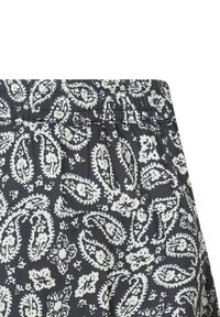 Shorts en tissu noir avec un imprimé paisley blanc. Dotés d'une taille élastique et d'une texture lisse. Les motifs sont dispersés de manière prononcée.