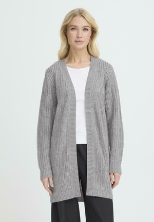 Grå stickad kofta med öppen front, texturerat mönster, långa ärmar och ribbade ärmslut. Bärs över en vit topp och svarta byxor.