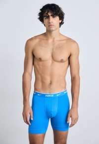 Blue boxer briefs with a white elastic waistband featuring Nike branding, made from a smooth, stretchy material for comfort and support.