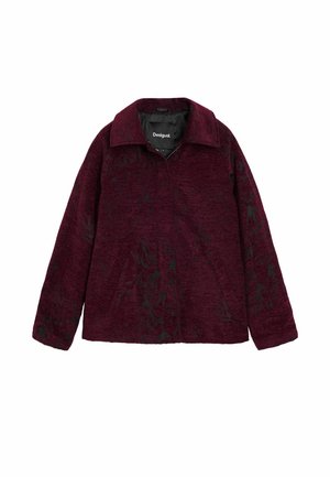 Burgundy zip-up jacket with a textured finish and black floral patterns. Features a classic collar and two front pockets.