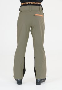 Olivegrüne Skihosen mit einem schwarzen unteren Akzent, elastischem Taillenbund mit Logo und einer Reißverschlusstasche mit einem orangen Zugband.