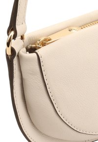 Crème leren handtas met een ronde vorm, voorzien van gouden hardware en een ritssluiting, geaccentueerd met donkerbruin stiksels.