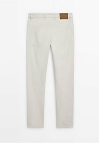 Jean beige droit avec deux poches arrière, passants pour ceinture et un patch de marque en cuir marron sur la ceinture.