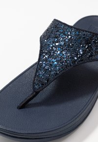 Marineflip-flop med teksturert såle og en thong-stropp dekket i mørkeblå og svart glitter. Glatt overmateriale.