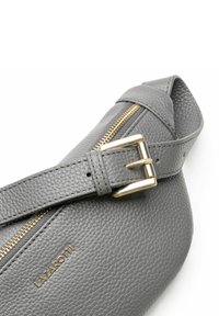 Graue Leder-Umhängetasche mit strukturierter Oberfläche, ausgestattet mit einem Reißverschluss in goldfarbener Ausführung und Riemen mit Schnallen-Detail. Logo auf der Seite geprägt.