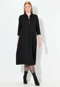 Czarna sukienka wykonana z miękkiego materiału, z kołnierzykiem, półdługimi rękawami, zapinana na zamek z przodu oraz plisowanym wzorem, sięgająca do połowy łydki.