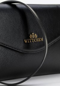 Clutch de cuero negro con un acabado texturizado, que presenta un logo dorado de "Wittchen" y una correa para el hombro delgada y flexible.