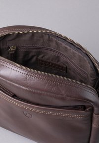 Brown leather bag with a zip closure, featuring an interior zip pocket and a smooth texture with contrasting stitching details.