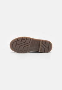 Brun gummi såle med teksturert gripe mønster, rektangulære flekspunkter og et flatt design med en jevn kantfinish.