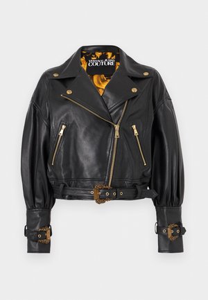 Giacca da motociclista corta in pelle nera con dettagli dorati, fibbie decorative, zip frontale e fodera a motivo giallo-nero.