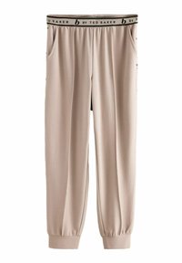 Beige joggerbukser med ribbet tekstur, elastisk talje med en sort label og sidelommer. Bunden er manchetteret for en tætsiddende pasform.