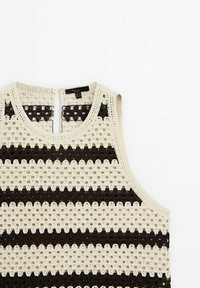 Canotta all'uncinetto con un motivo a righe crema e marrone scuro, scollatura rotonda e chiusura a bottoni sul retro. Presenta una texture a maglia aperta.
