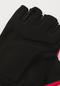 Gant sans doigts noir avec des accents rouges, fabriqué en néoprène doux. Présente des rembourrages, des détails de couture et des sections perforées pour la respirabilité.