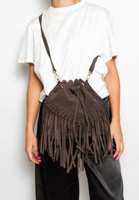 Borsa in suede marrone con chiusura a coulisse e lunga frangia decorativa. Cinghia regolabile e rifiniture in metallo dorato.