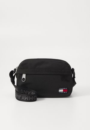 Mała czarna torebka na ramię z zamkiem błyskawicznym, regulowanym paskiem z logo marki oraz naszywką z logo Tommy Jeans z przodu.